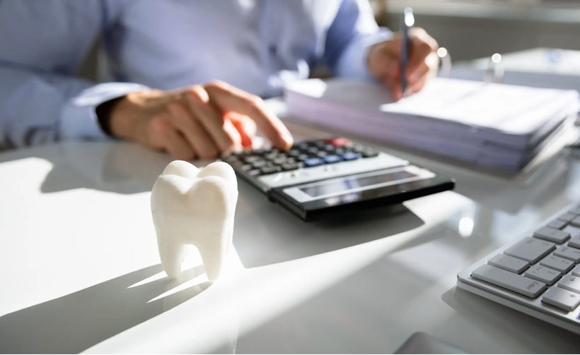 person calculating dental costs with the model tooth, symbolizing Aetna insurance coverage