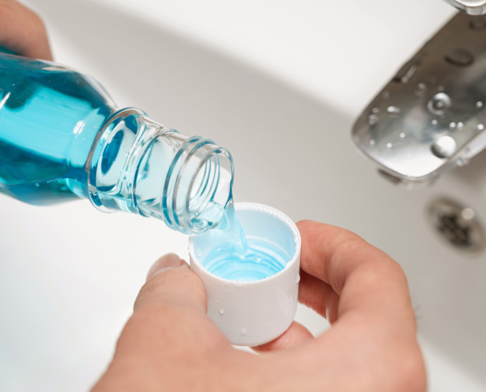 pouring blue fluoride mouthwash into a cap for dental treatment in alexandria